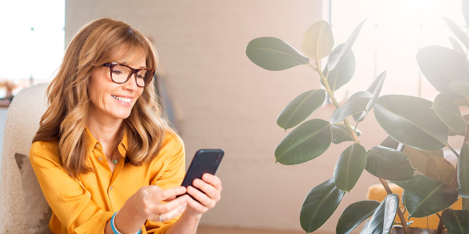 Woman with glasses intently looking at her phone, exploring Lift Dental’s services and scheduling her next dental appointment online