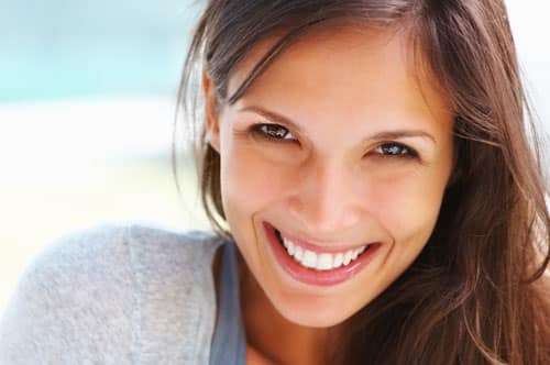 A woman beams with a radiant smile, her teeth visible, illustrating the transformative power of cosmetic dentistry for a perfect smile