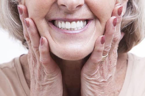 Close-up of an elderly woman smiling, showing healthy teeth, highlighting the benefits of restorative dental care