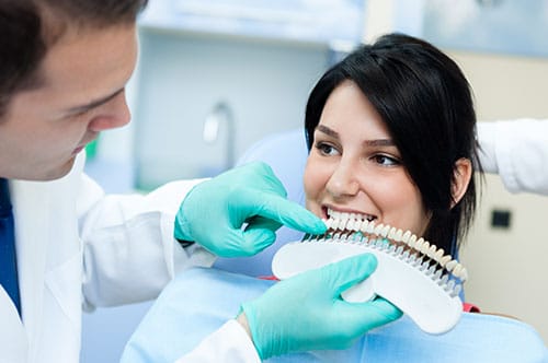 A woman undergoing a dental check-up, with the dentist carefully examining her veneers for optimal oral health