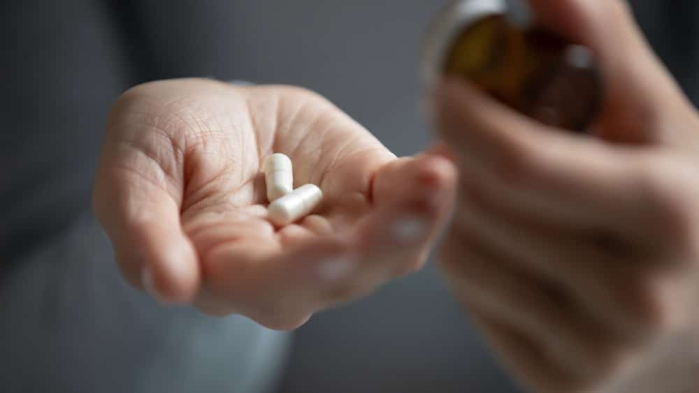 Individual grasping a pill and a bottle of pills, representing the concept of oral sedation treatment