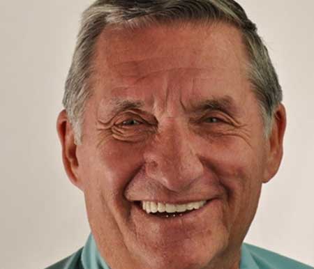 A cheerful dentist wearing a blue shirt, presenting a warm smile that accentuates his white teeth and positive attitude