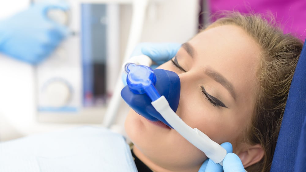 Woman undergoing a dental cleaning while comfortably sedated with nitrous oxide, ensuring a relaxed experience during the procedure