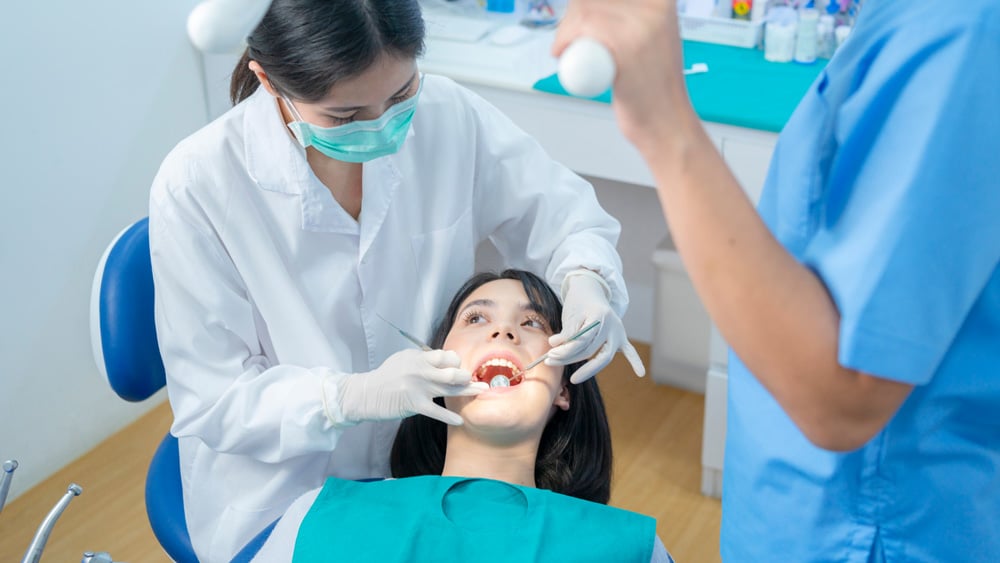 Woman receiving dental sealants from her dentist in Stillwater, MN, with the dentist's assistant standing beside them